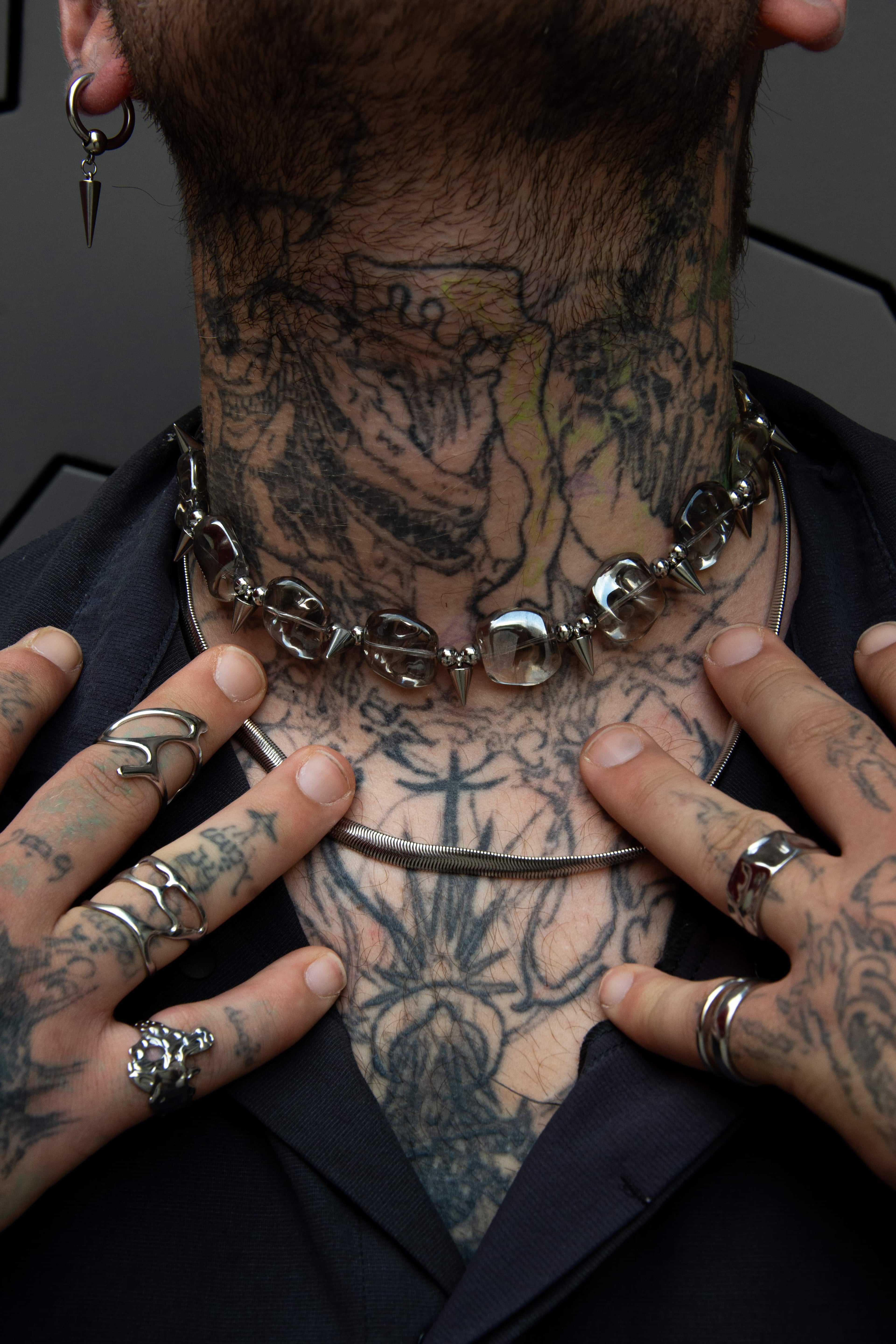 Assortiment de bijoux au style alt en acier inoxydable porté par un mannequin très tatoué.