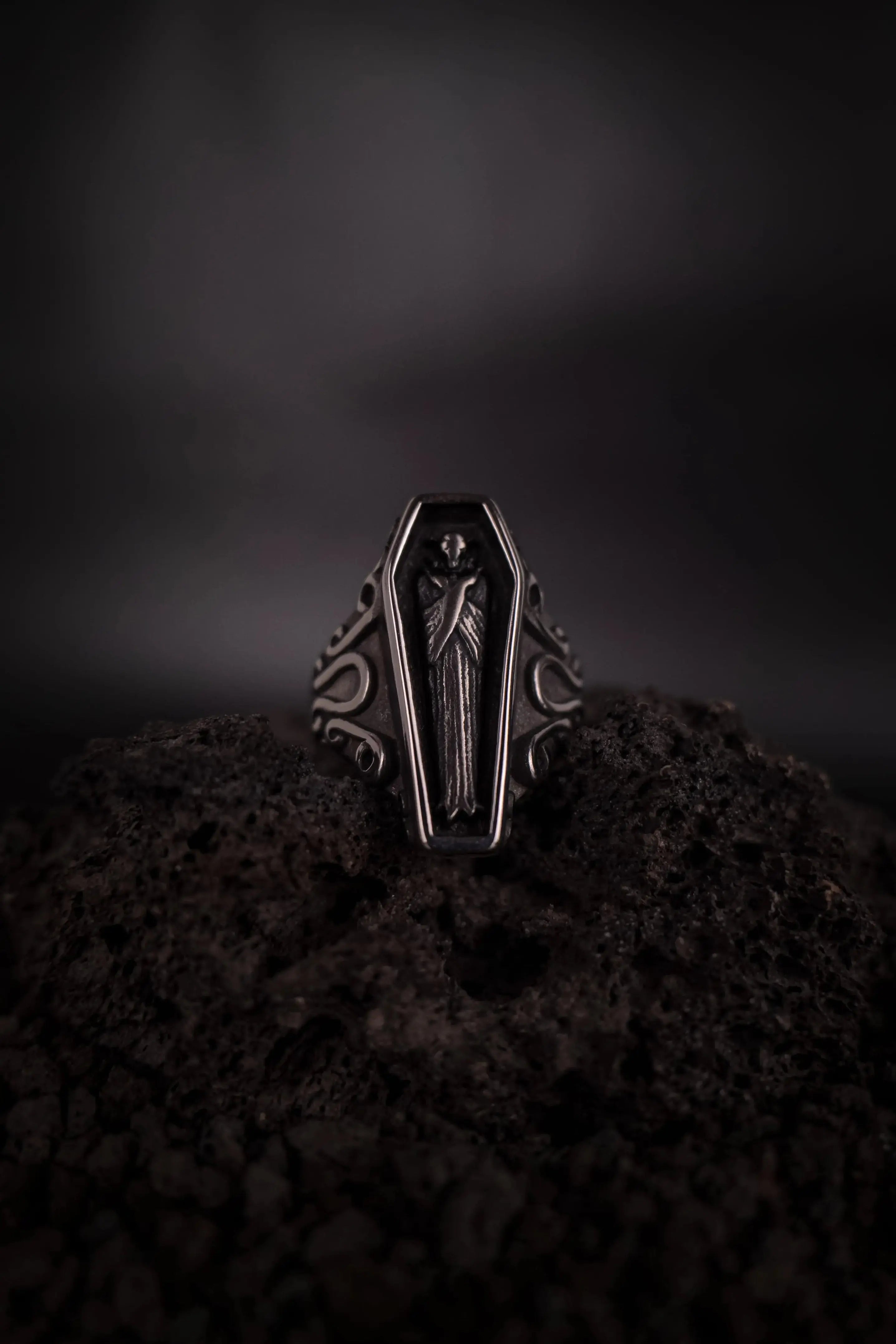 Bague vampire dans un cercueil en acier inoxydable, bague mixte style alternatif posé sur de la roche volcanique, pierre de lave 