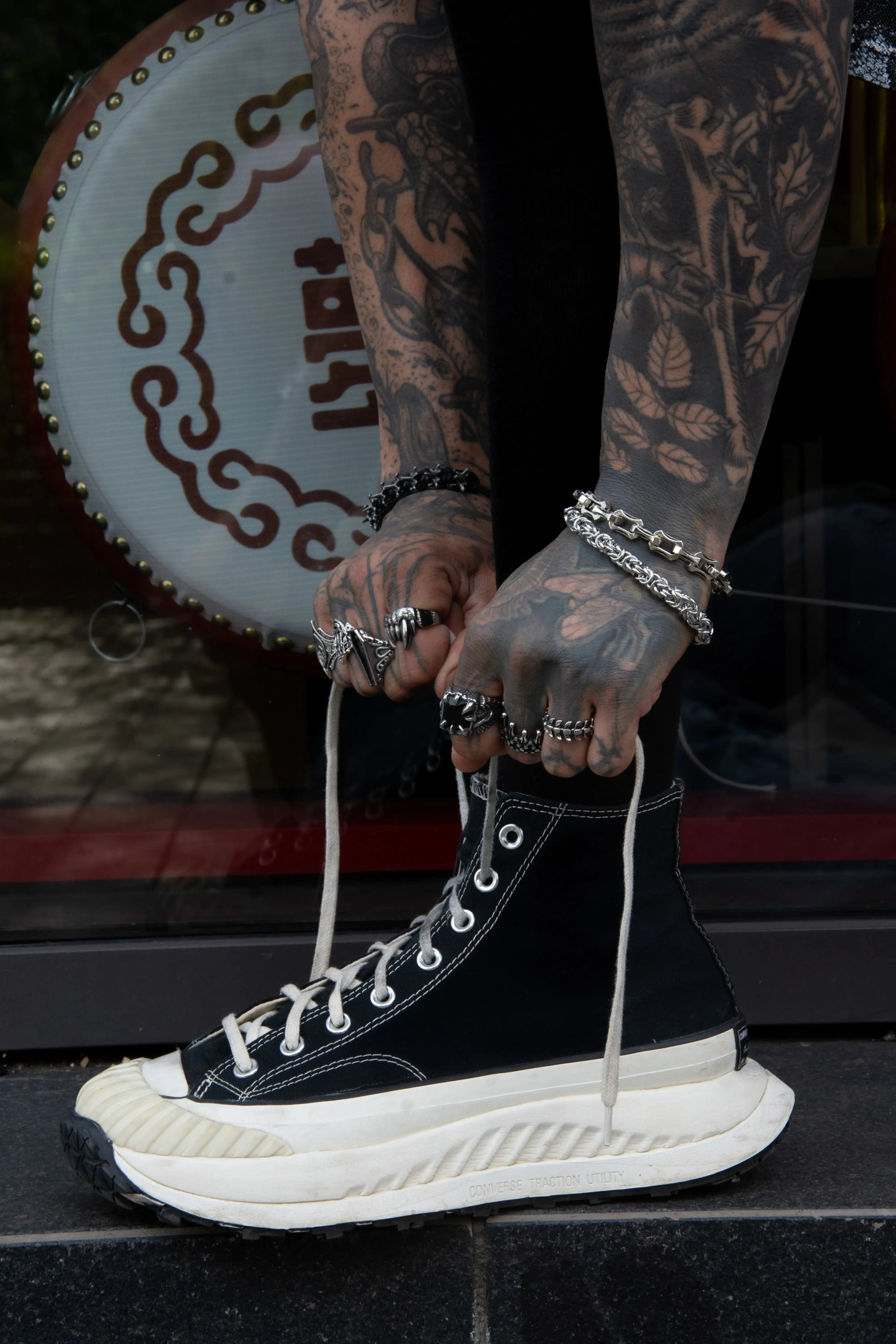 Deux mains qui lace des chaussures elle portent des bijoux forgés en acier inoxydable de qualité. Une bague os