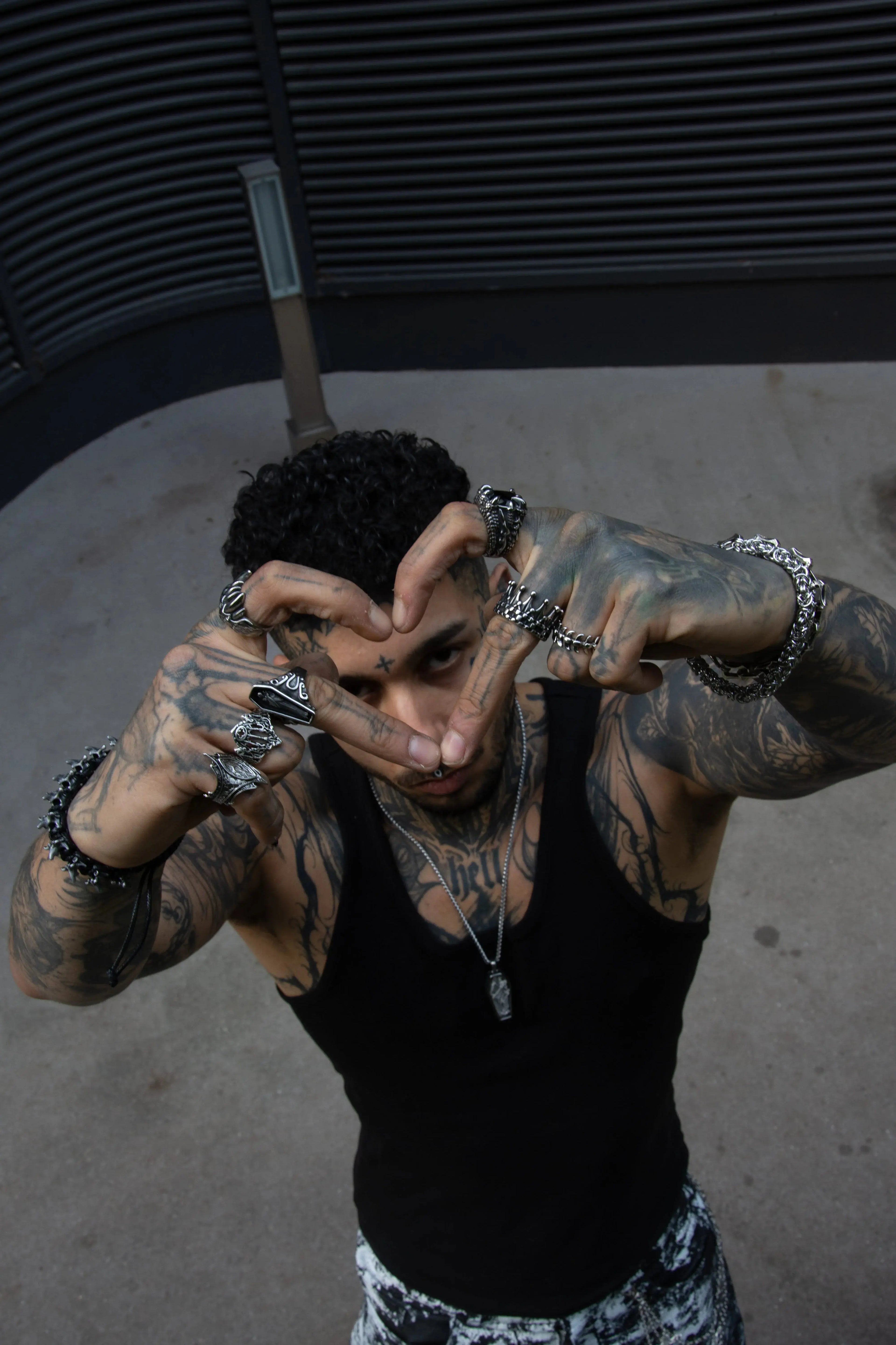 Mannequin tatoué qui fait un coeur avec ces doigts, il porte des bijoux bagues rock en acier inoxydable des bracelet chaine et un pendentif cercueil.