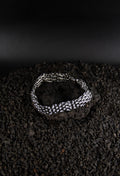 Chaîne bracelet plate en acier inoxydable posé sur roche volcanique noir