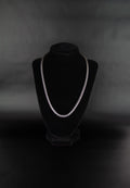 Collier chaîne torsadée en acier inoxydable posé sur un présentoir à bijoux en velour noir sur fond noir.