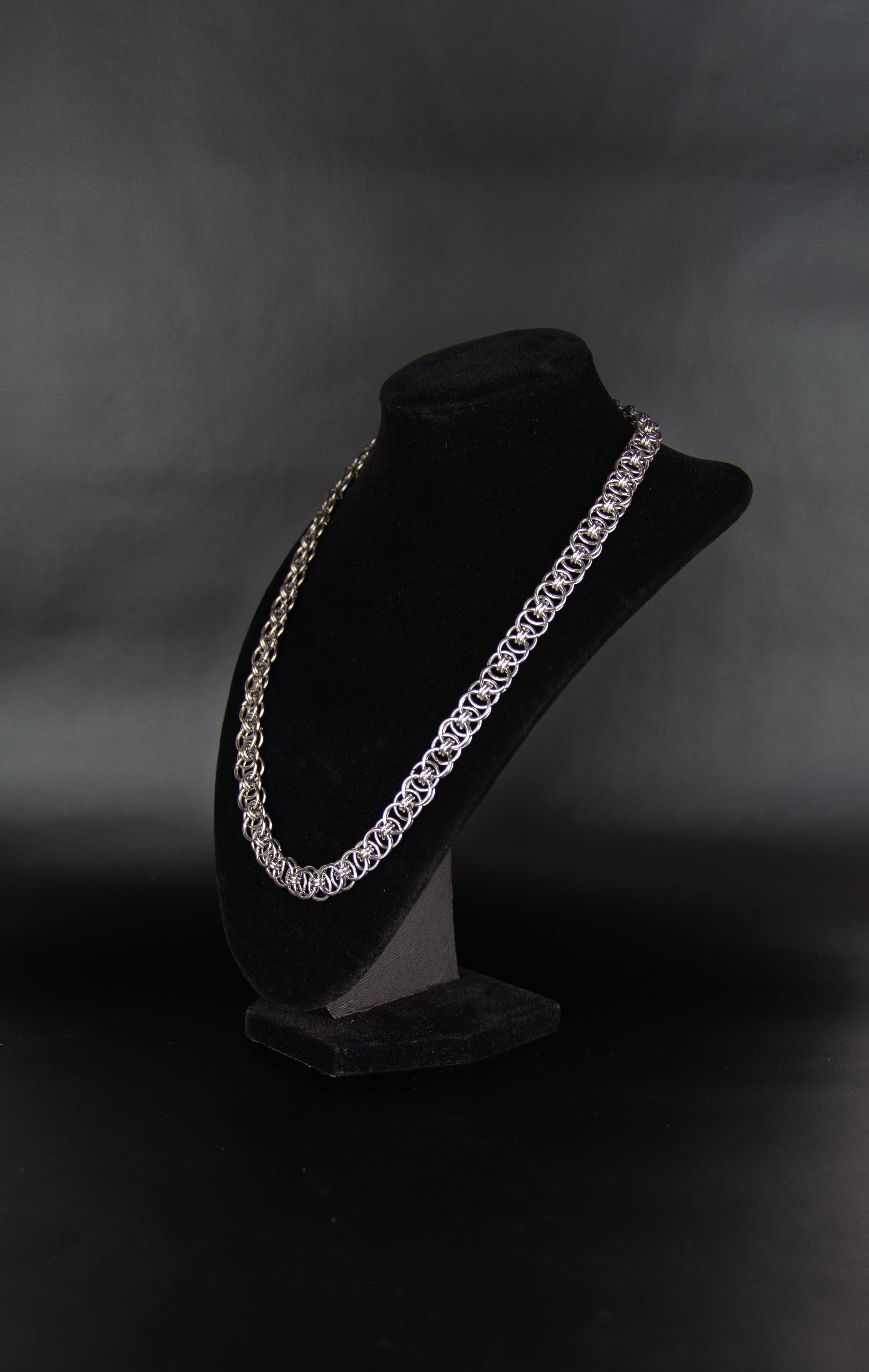 Chaine à maillon ouvert en acier inoxydable posée sur un présentoir bijoux en velours noir de trois quarts.