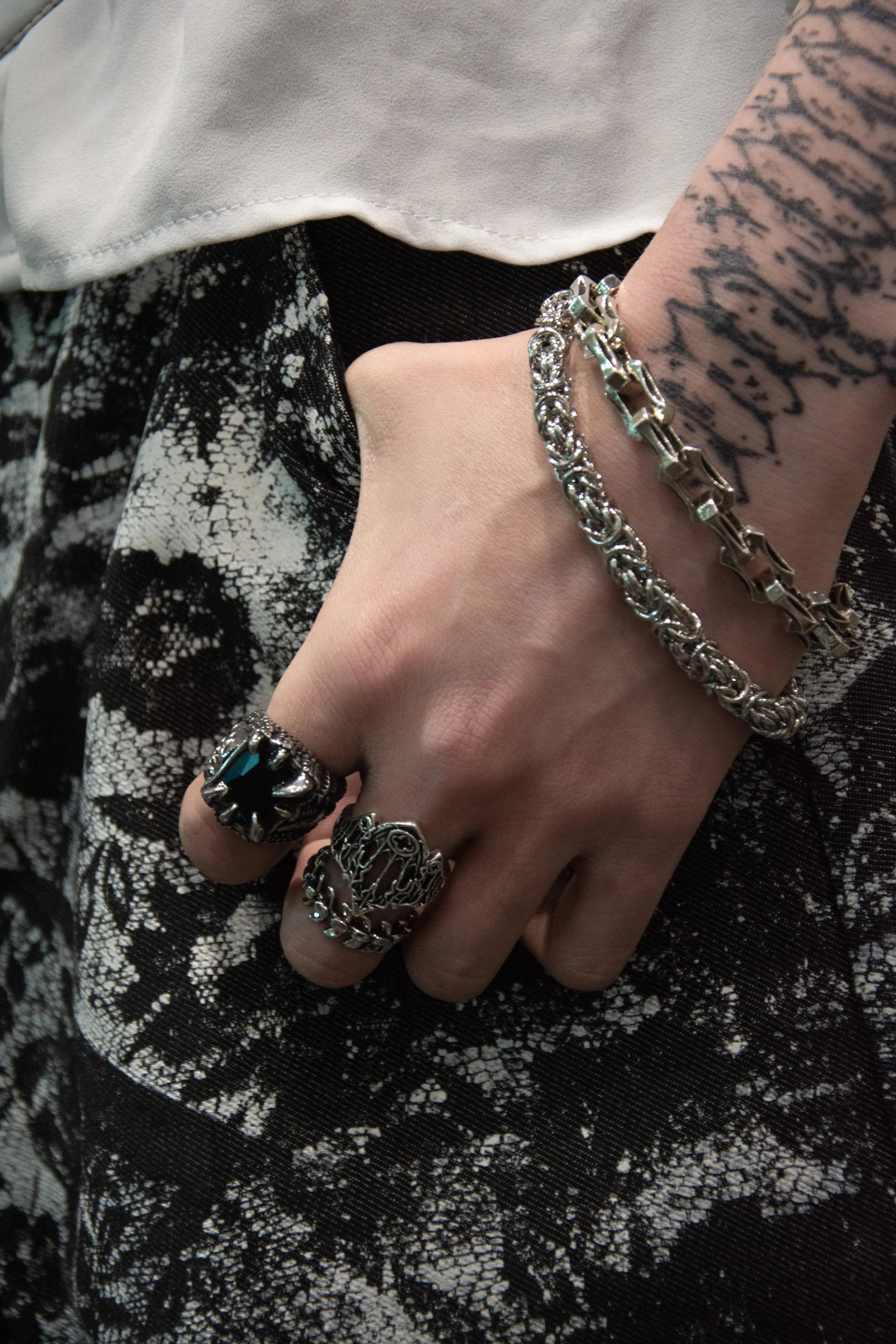 Femme tatoué portant des bracelets en acier inoxydable et des belles bagues gothique, cathédrale, squelette et griffe serti une pierre noir