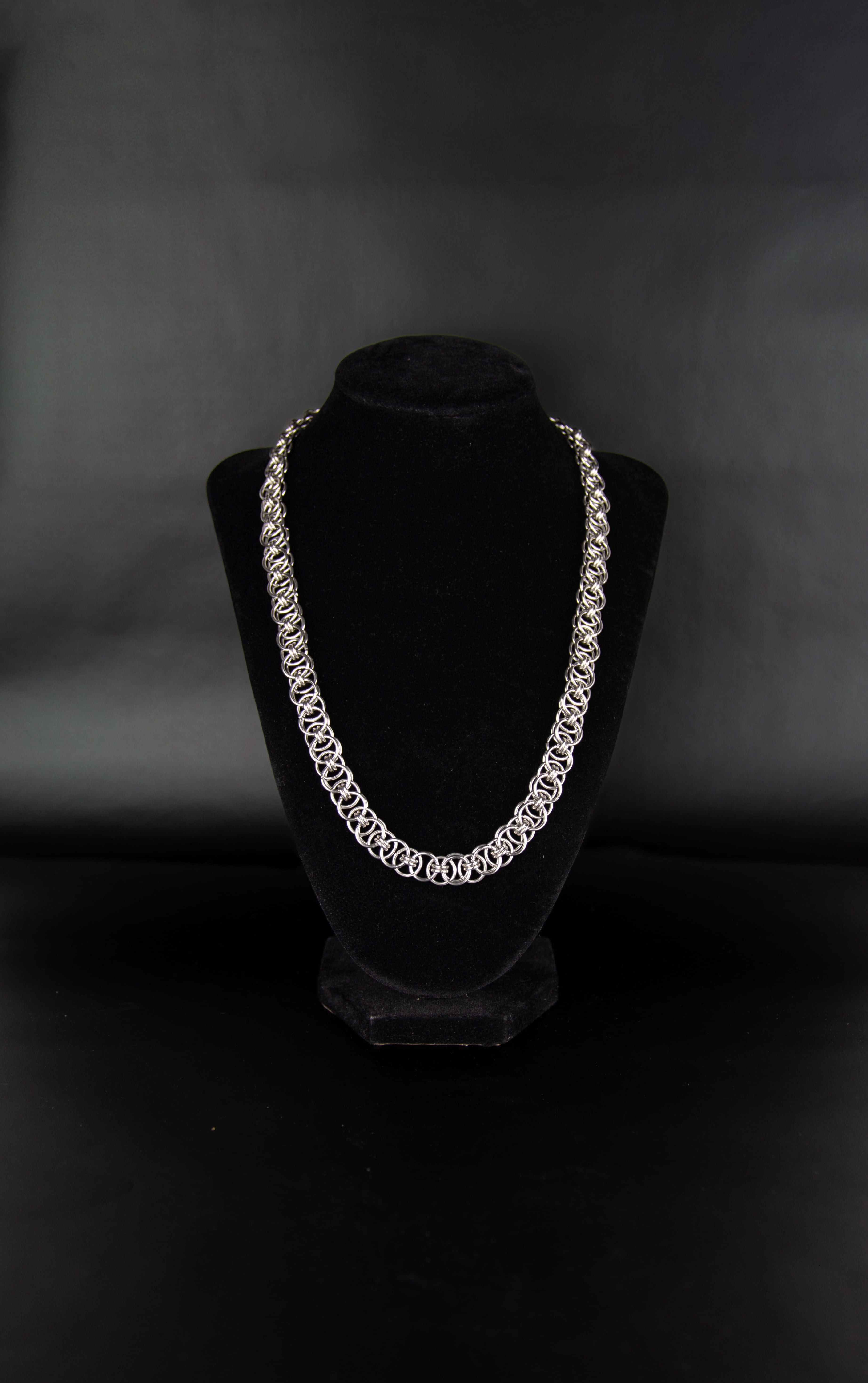 Chaine à maillon ouvert en acier inoxydable posée sur un présentoir bijoux en velours noir.