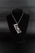 Collier étui à briquet en acier inoxydable posé sur un présentoir en velours noir.