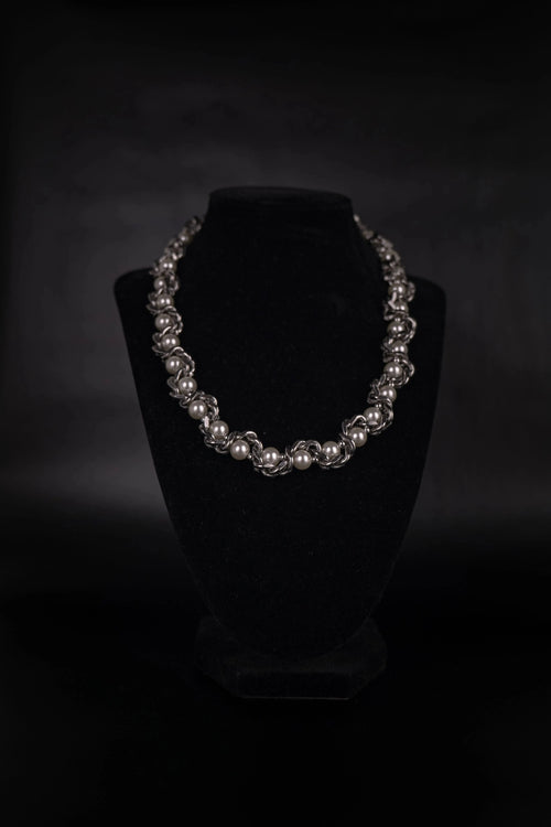 Un collier fais d'une chaine en acier inoxydable entrelacée de perles blanc nacré mélangeant effet brut du métal et raffiné des perles. Collier mixte.