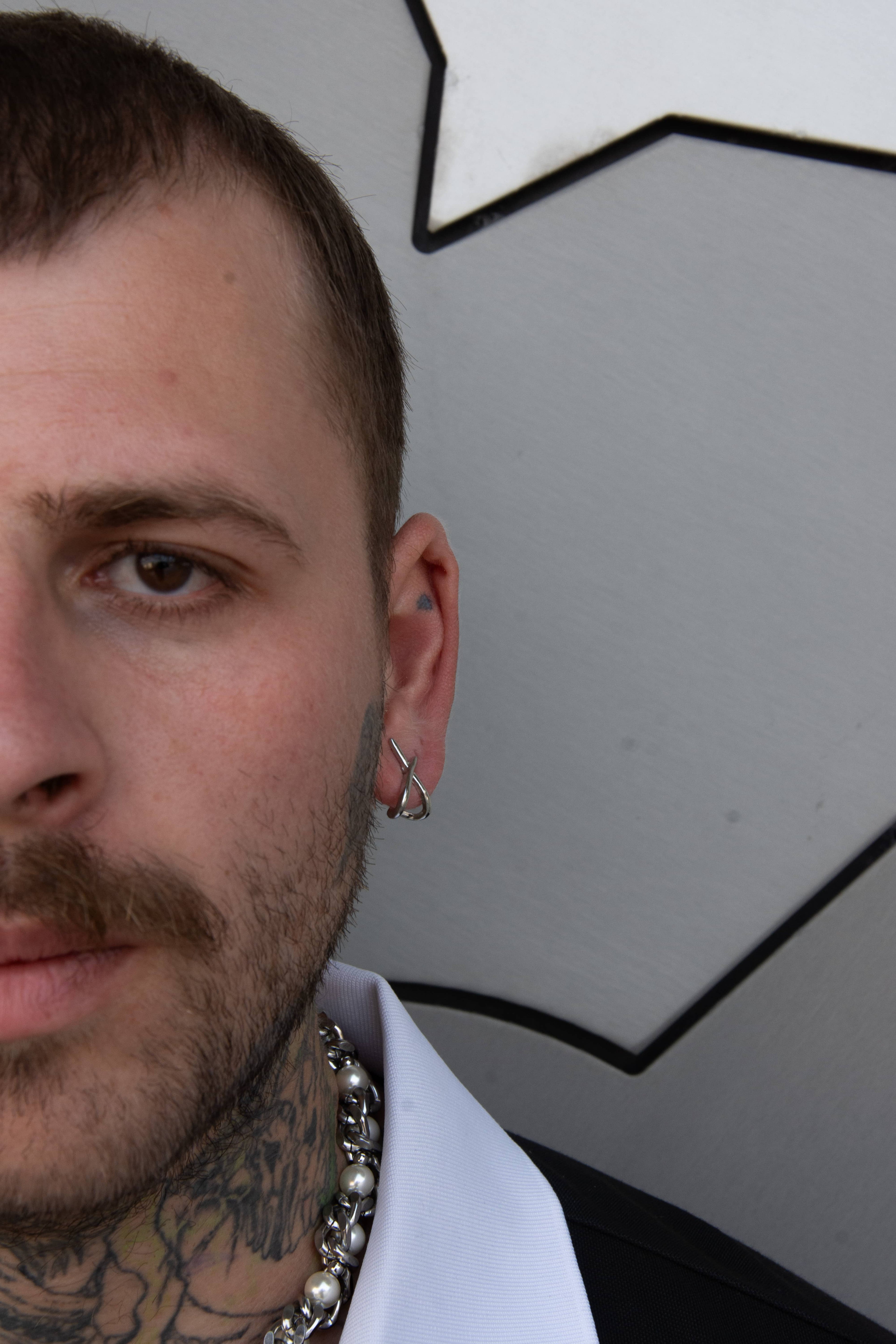 Mannequin homme portant paire de boucle d’oreille en forme de X et collier de chaîne et perles 