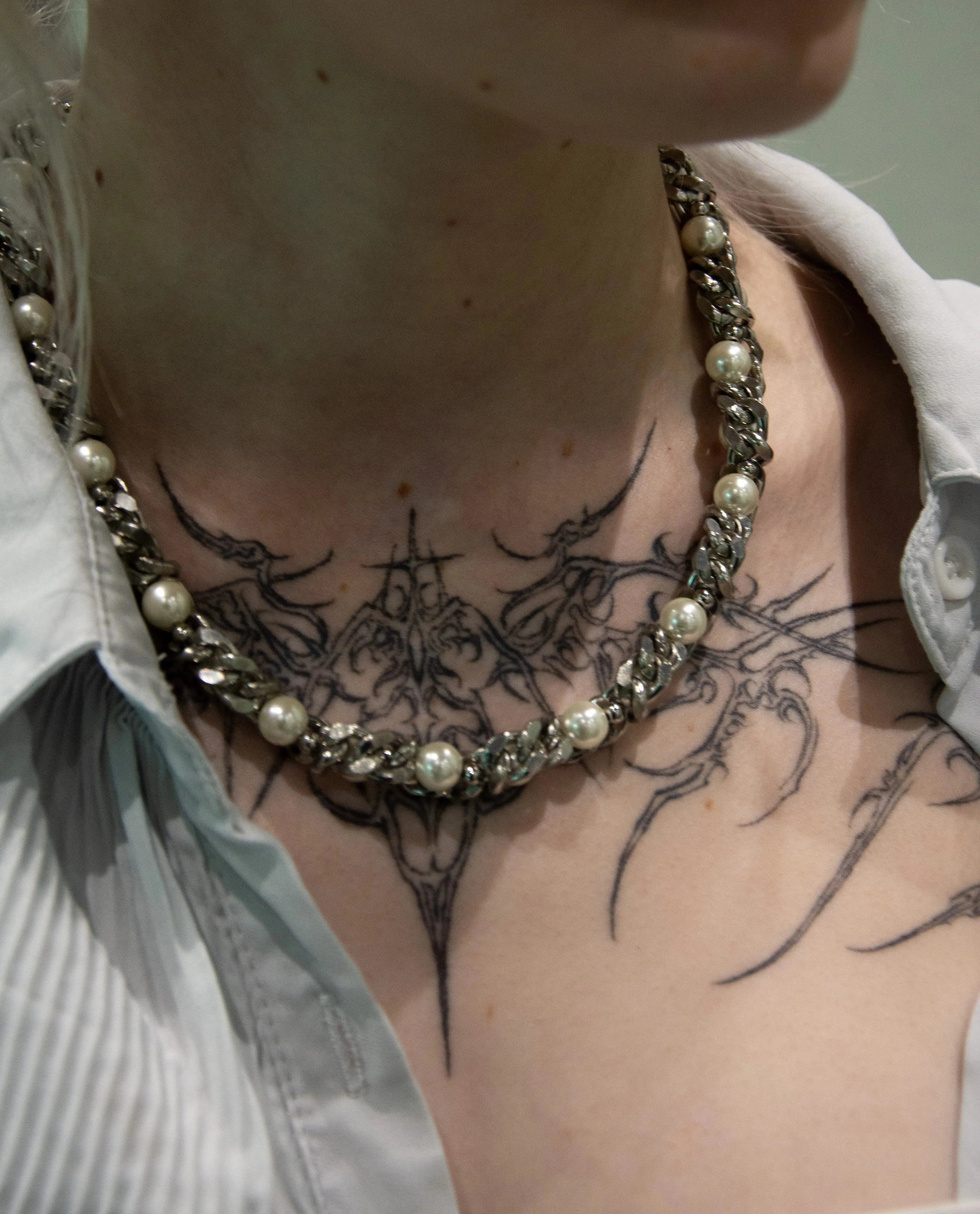 collier chaine enlacé avec des perles blanche nacré, collier original au style alt porté par une mannequin tatoué  